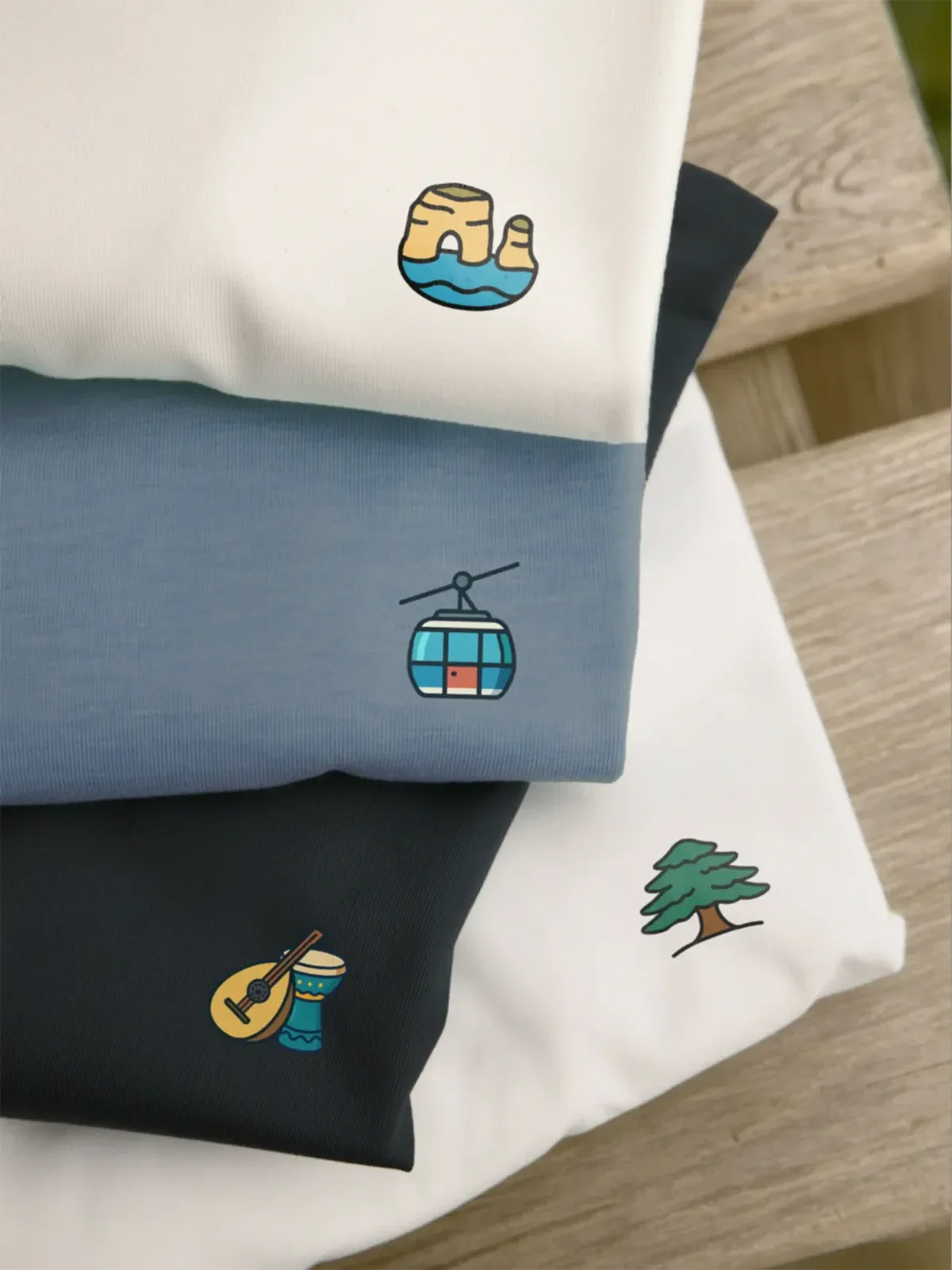 Stack of t-shirts and sweatshirts with the Raouche, Teleferique, Music Duo and Cedar designs for the Lebanon Minis collection by inspire.inc