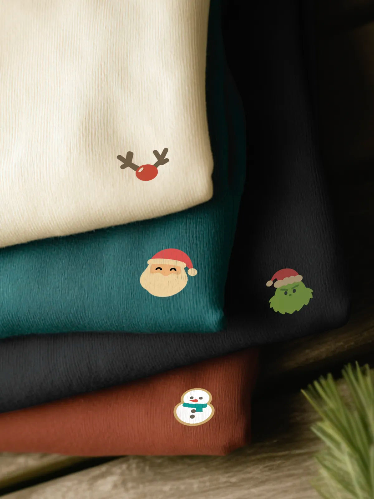 A white, blue, black and red sweatshirts stacked with designs from the Christmas Minis collection by inspire.inc