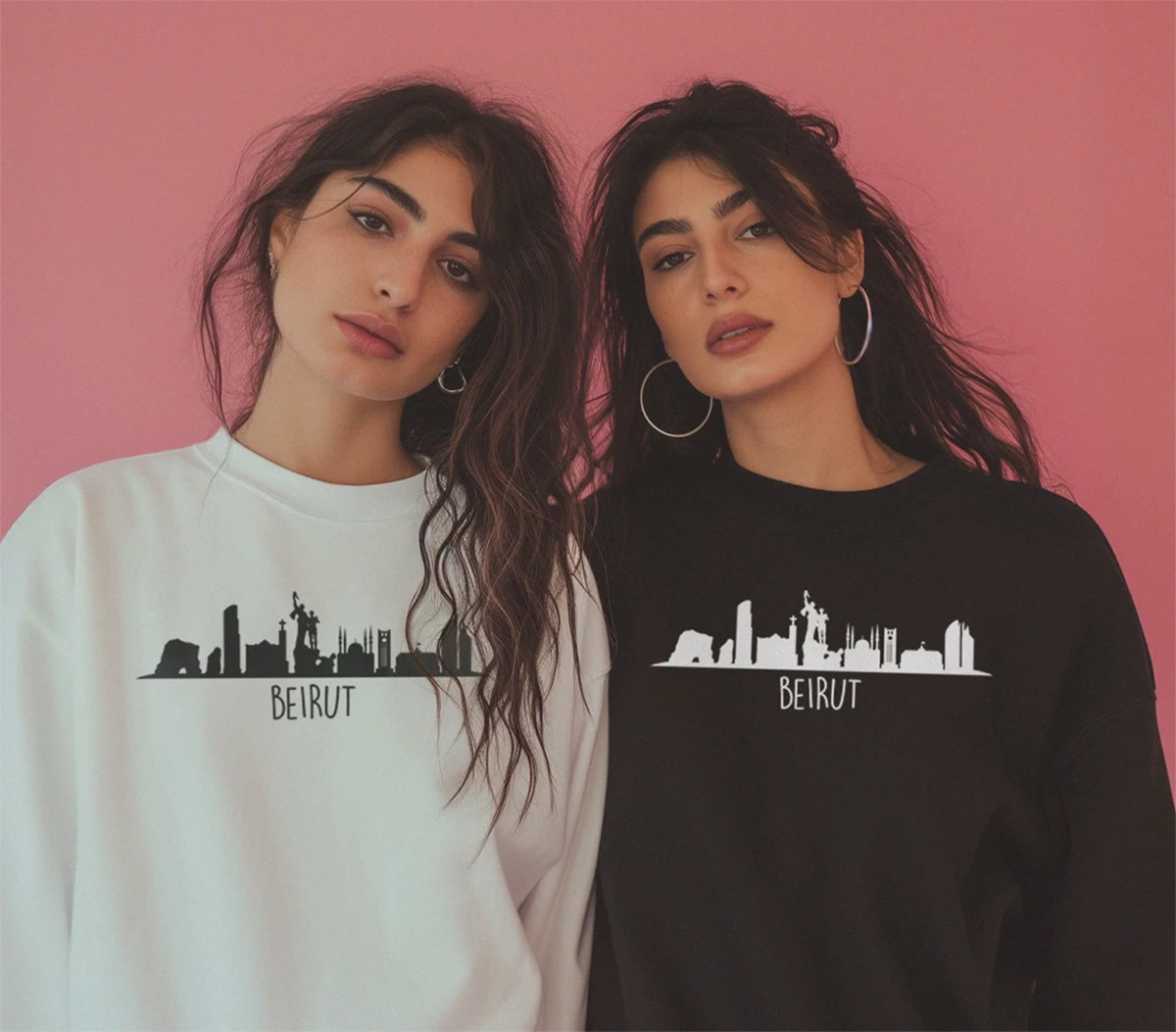 Two Lebanese women wearing a white oversized sweatshirt and a black oversized sweatshirt with the Beirut Skyline design by inspire.inc m